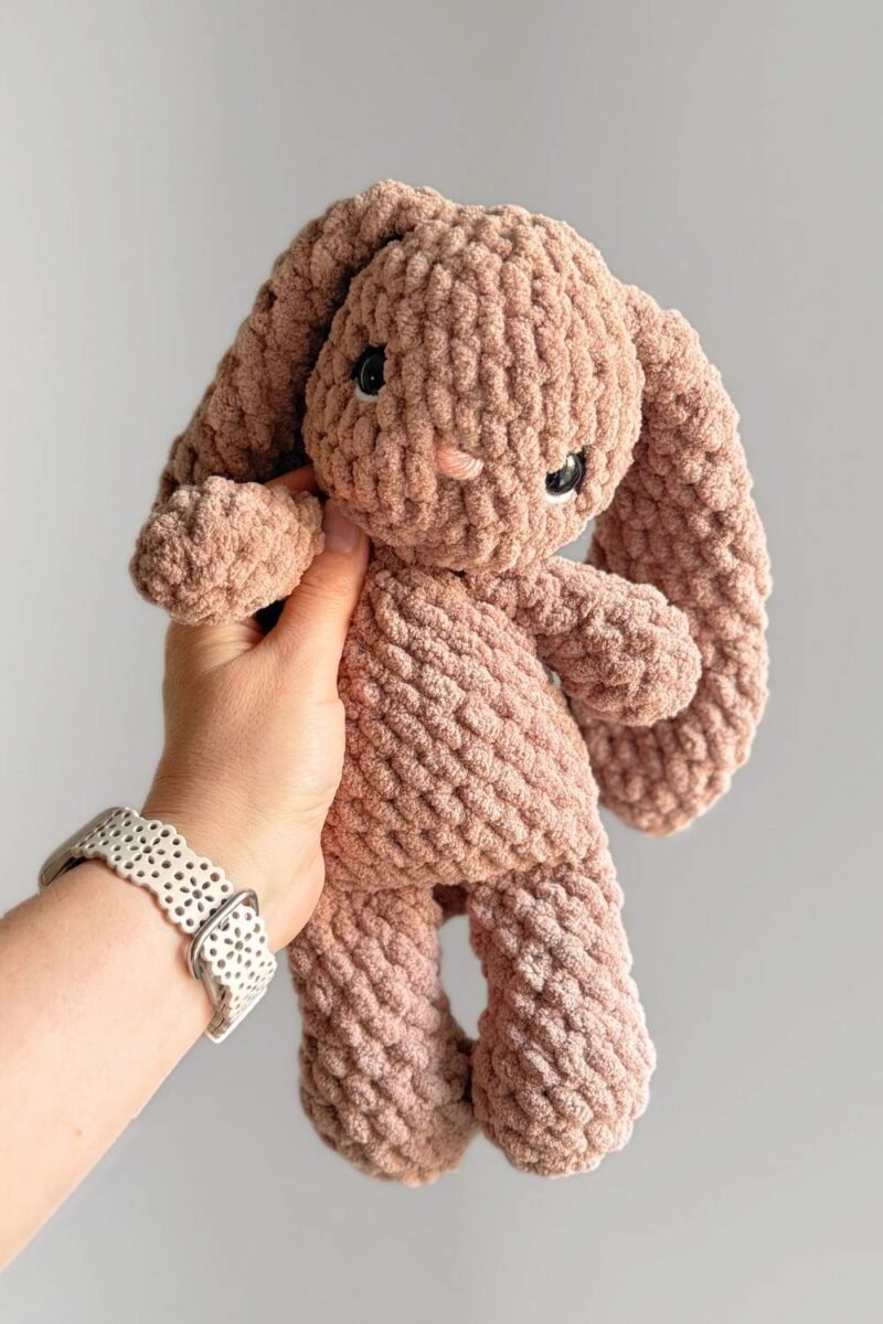 A brown crochet bunny with embroidered details on eyes.