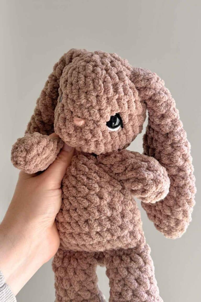 A brown crochet bunny with embroidered detailing added to her eyes.