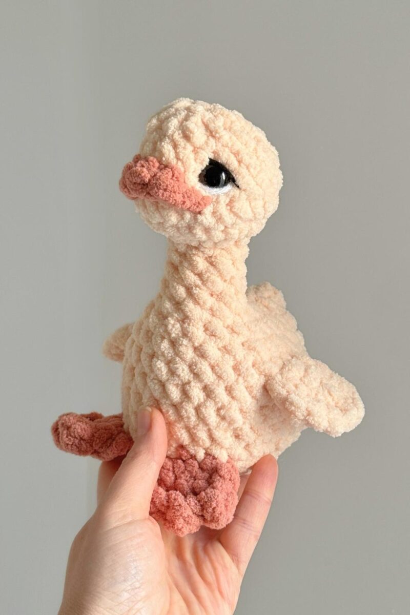 A yellow and orange goose with embroidery details added to her eyes.