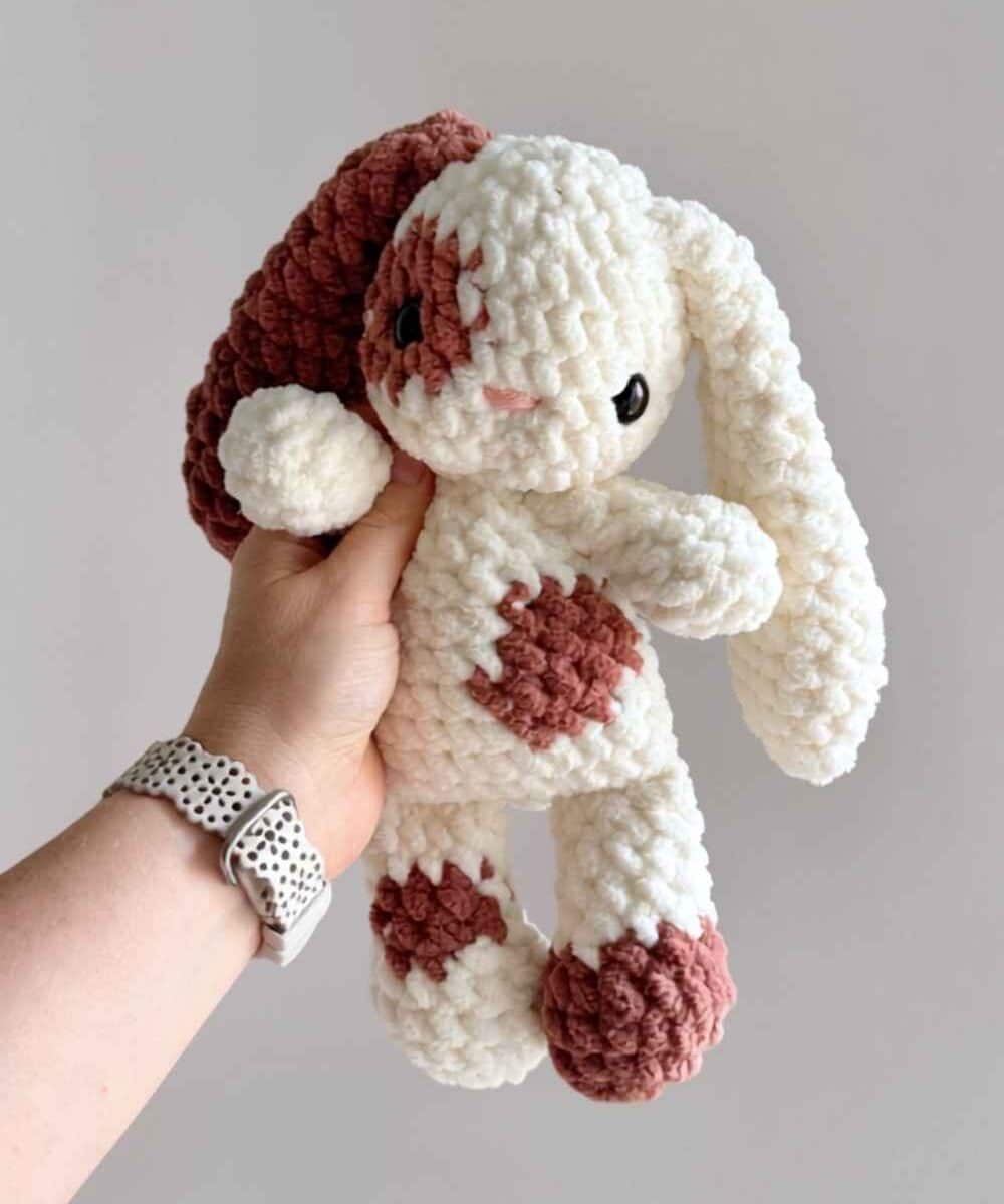 A brown and white floppy-eared crochet bunny.