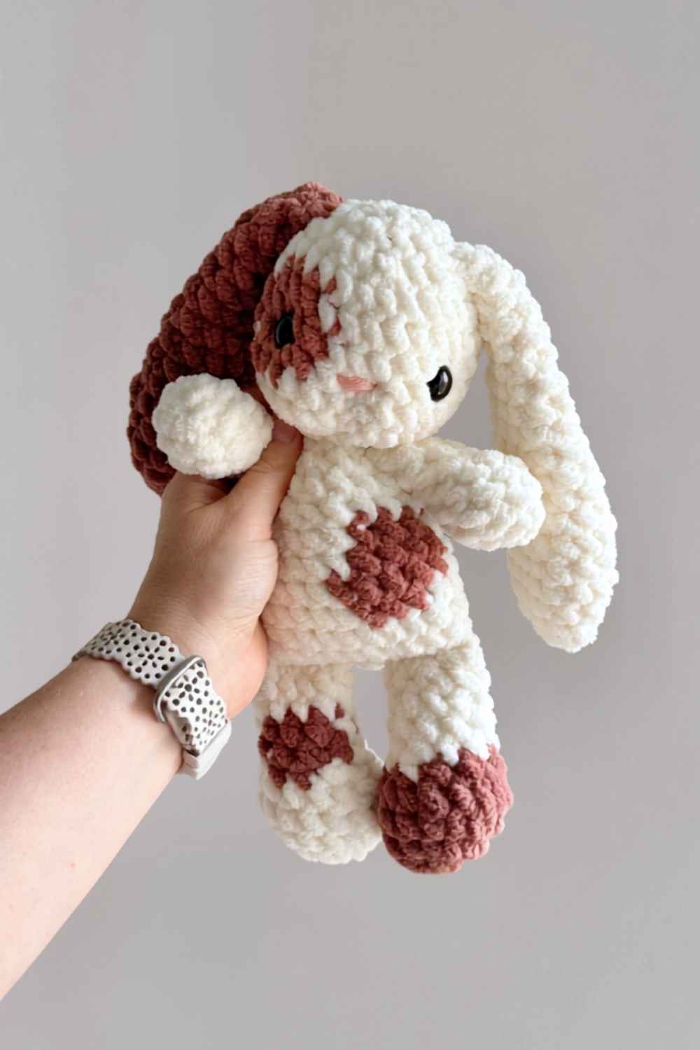 A brown and white floppy-eared crochet bunny.