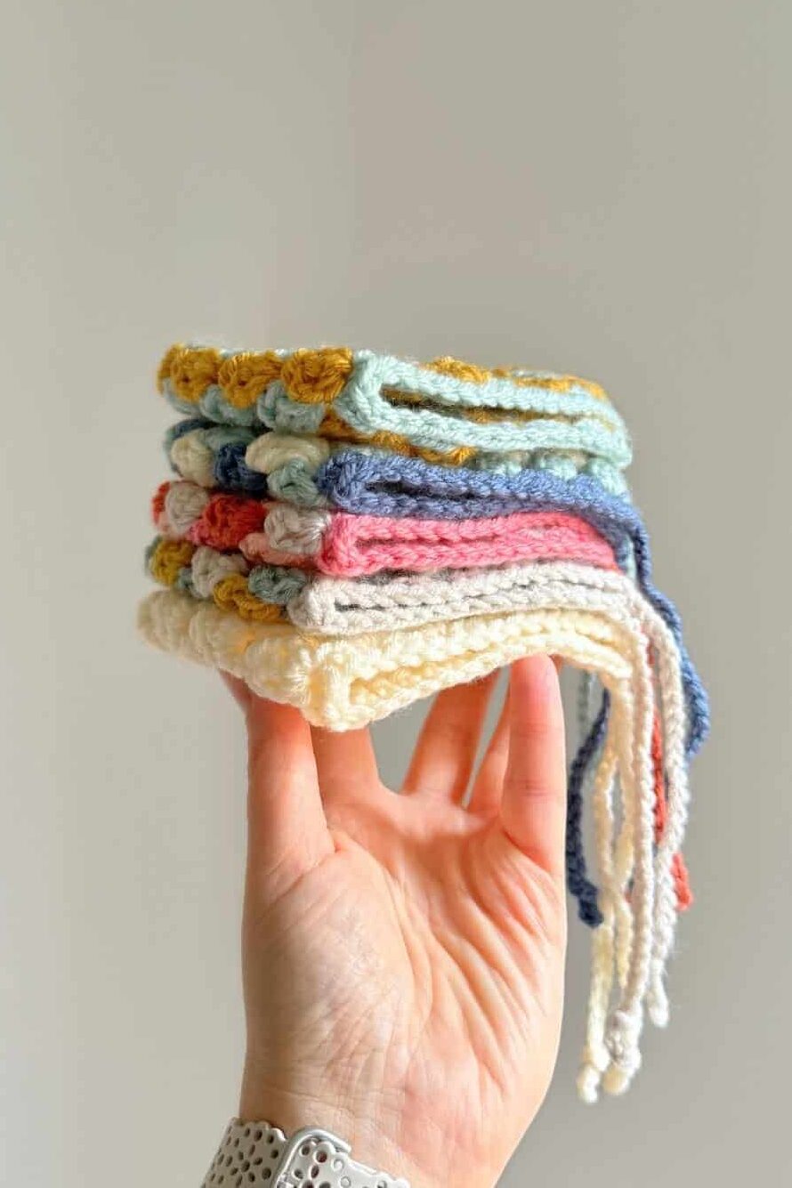 Hand holding a stack of crochet pixie hats in various color combinations.