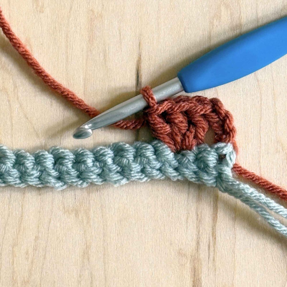 A photo showing the next step of completing row 2 of the crochet hat.