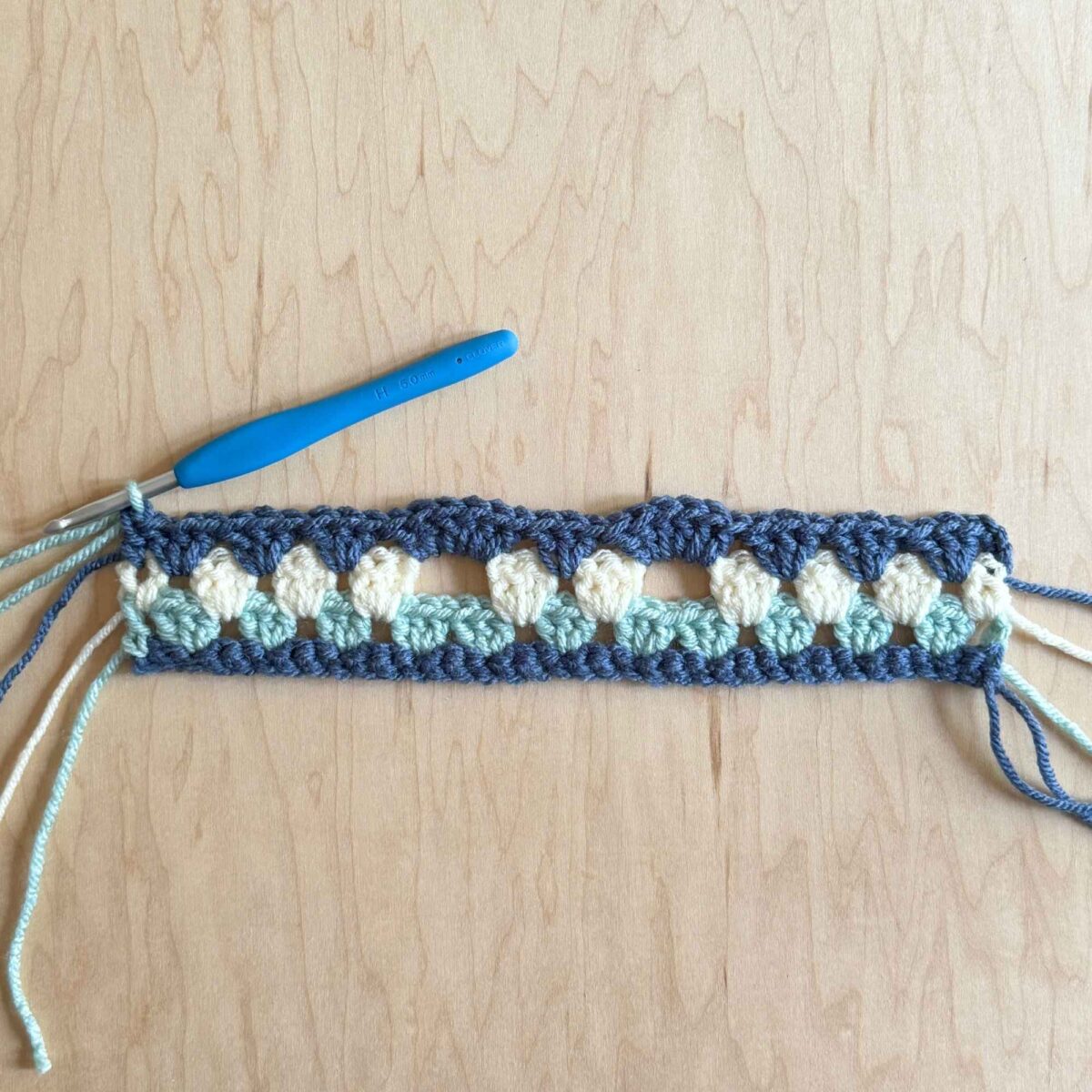 A photo showing row 4 completed with clusters of 6 half double crochet stitches.