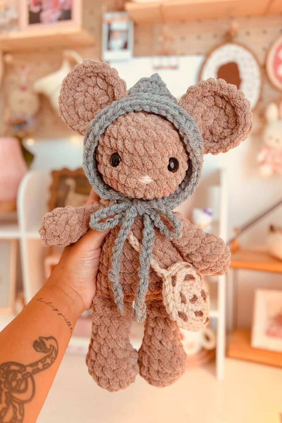 A brown crochet mouse wearing a cookie purse and crochet hat.