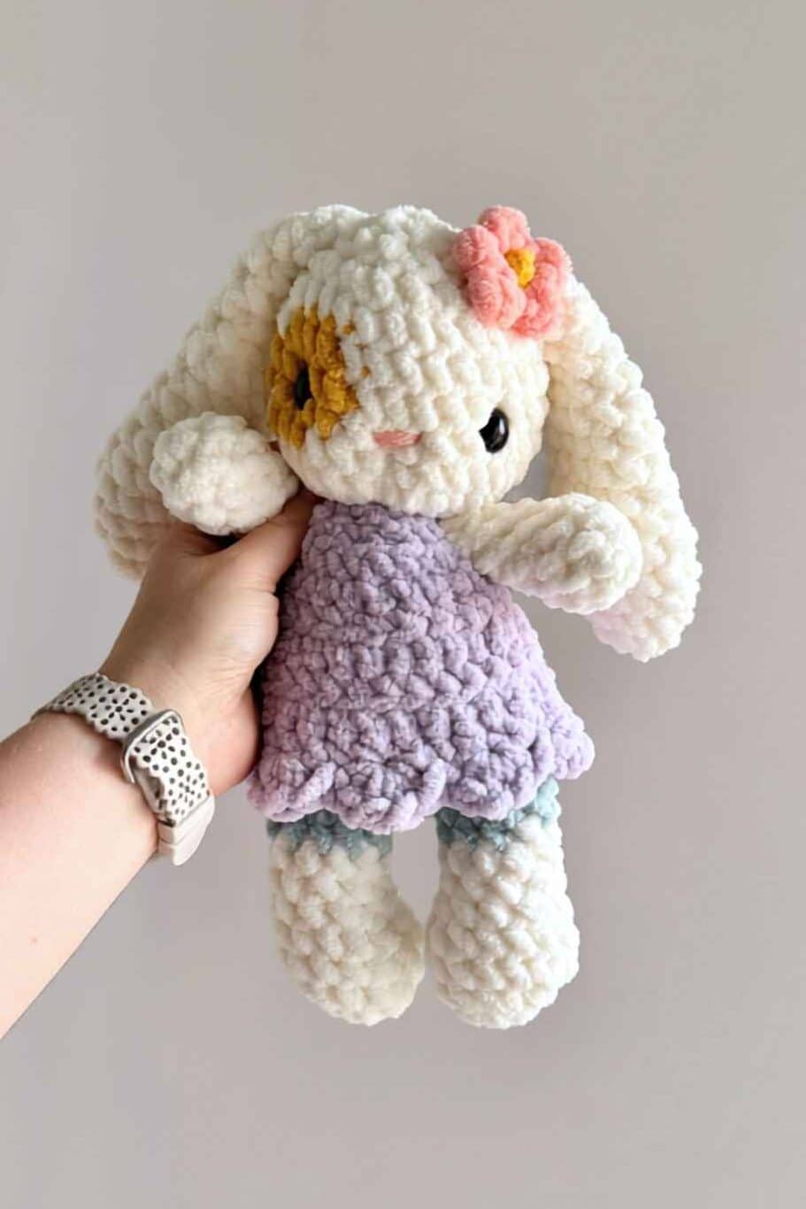 A larger crochet bunny wearing a purple crochet dress.