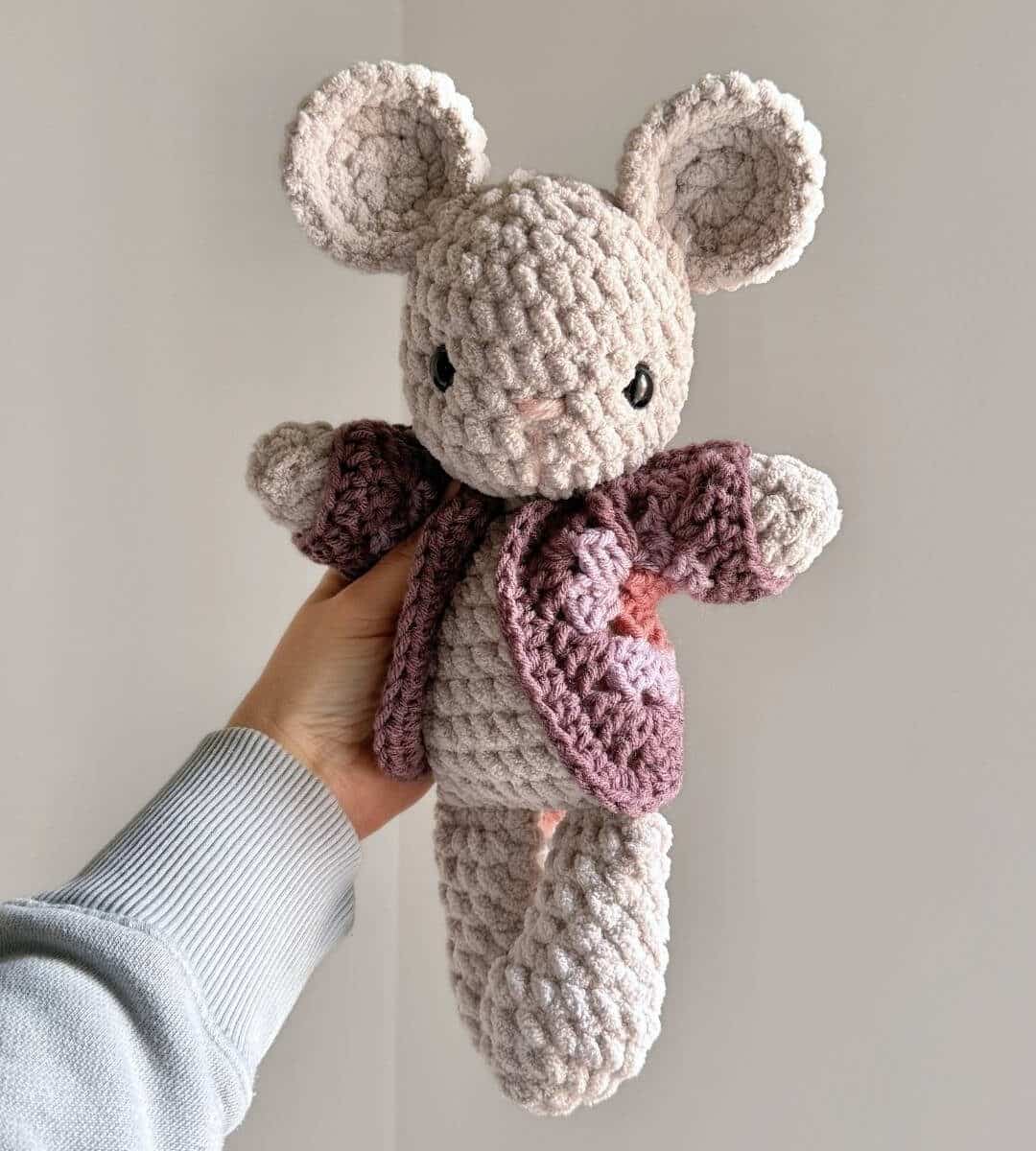 A gray crochet mouse wearing a purple crochet cardigan.