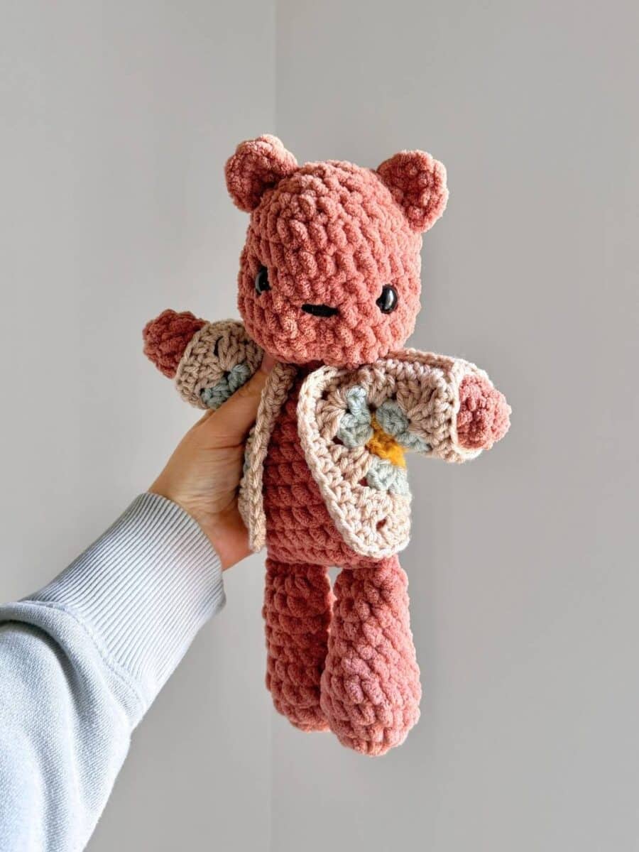 A brown crochet bear wearing a crochet sweater.