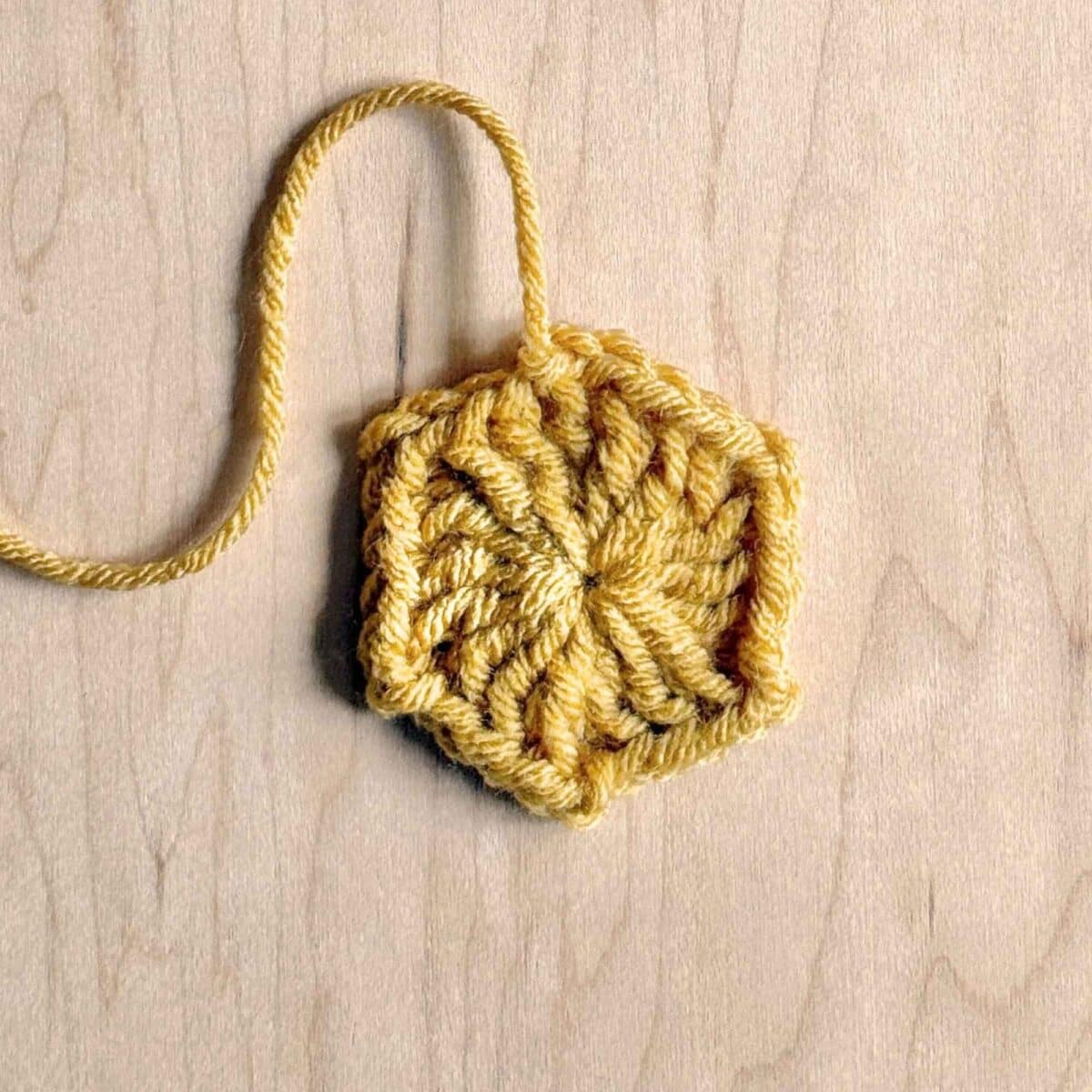 Process photo showing round 1 of the crochet hexagon with color changes.