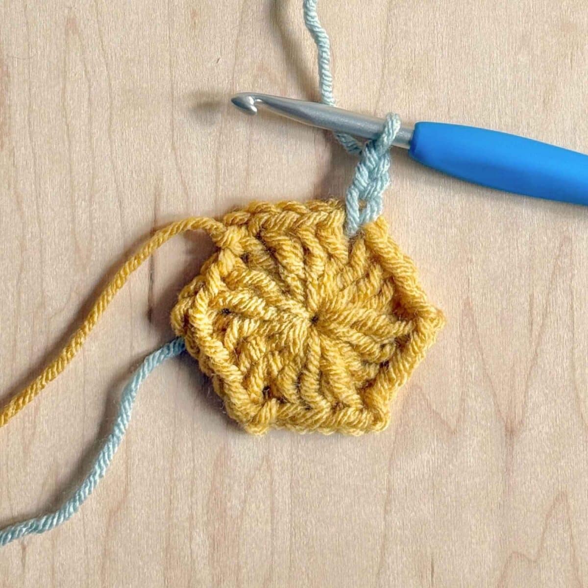 Process photo showing round 2 of the crochet hexagon with color changes.