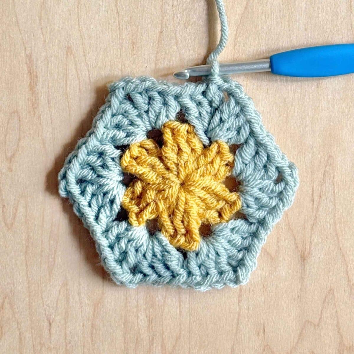 Process photo showing round 3 of the crochet hexagon with color changes.