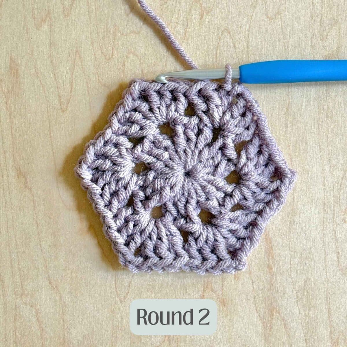 Process photo showing round 2 of the purple crochet hexagon.